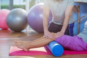Physiotherapist assisting woman while exercising on exercise mat