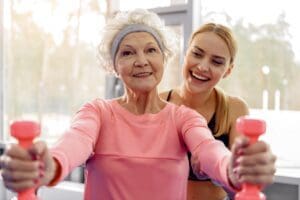 Cheerful grandmother making exercises in gym