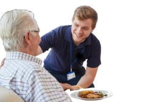 Male,Care,Worker,Serving,Dinner,To,A,Senior,Man,At