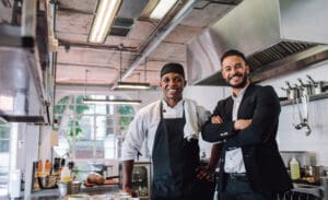 Portrait,Of,Restaurant,Owner,With,Chef,In,Kitchen.,Businessman,With