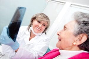 Dentist,With,An,Elder,Female,Patient,Looking,At,An,X ray