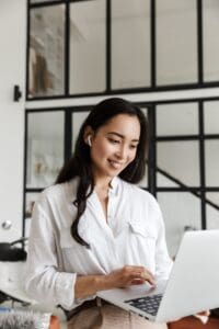 Attractive,Smiling,Young,Brunette,Asian,Woman,Using,Laptop,Computer,While