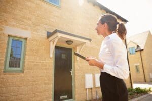 Female,Real,Estate,Agent,Looking,At,A,House,Exterior