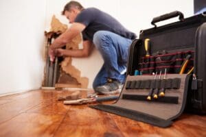 Middle,Aged,Man,Repairing,Burst,Pipe,plumbing,,Focus,On,Foreground
