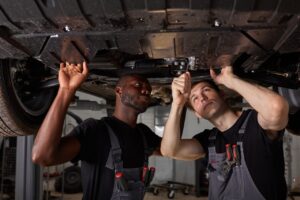 Two,Interracial,Car,Mechanics,In,Uniform,Checking,Car,In,Automobile
