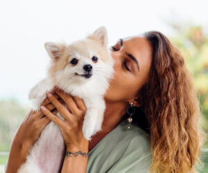 outdoor portrait of fluffy pomeranian dog being kissed by woman 1200x1000 1
